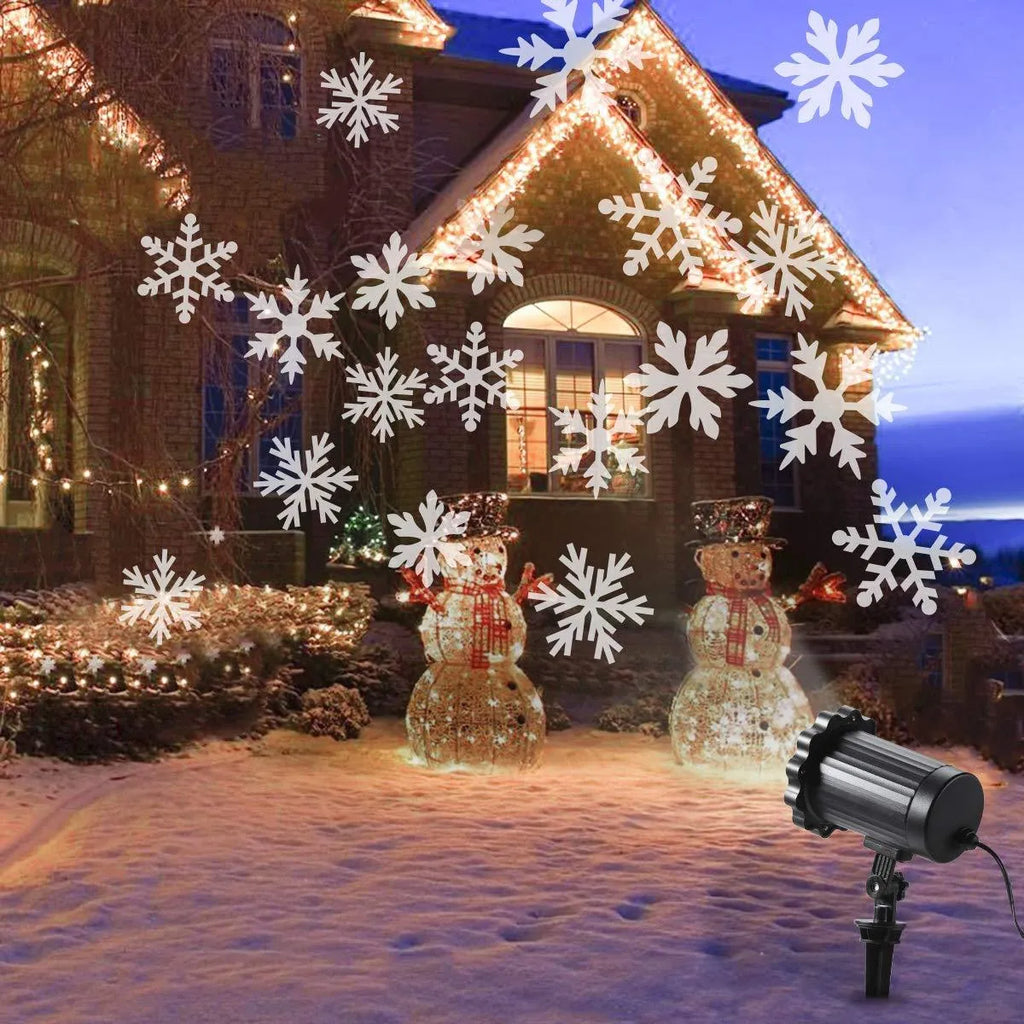 LED Christmas snowflake laser projector with white moving patterns on a dark garden wall at night