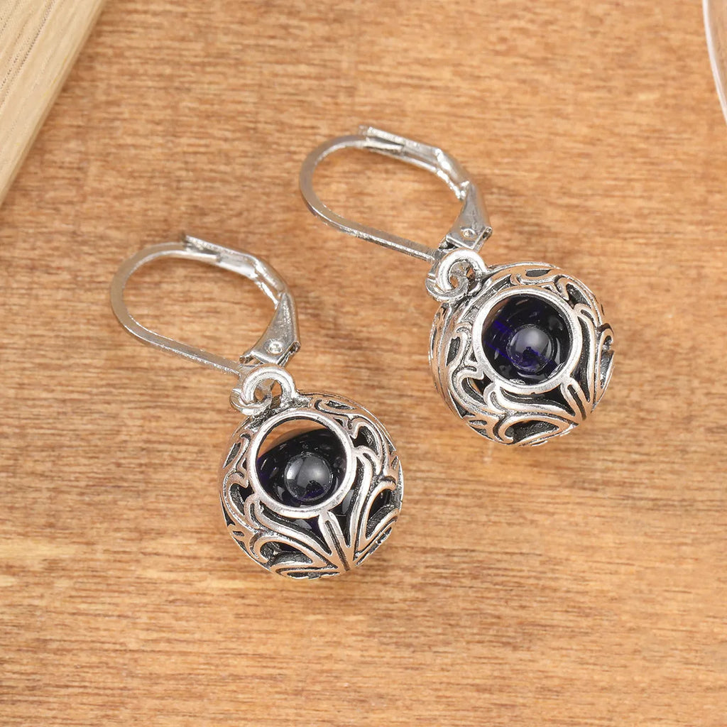 Silver geometric hollow pendant earrings with vintage engraving and a central blue gemstone on a zinc alloy setting.