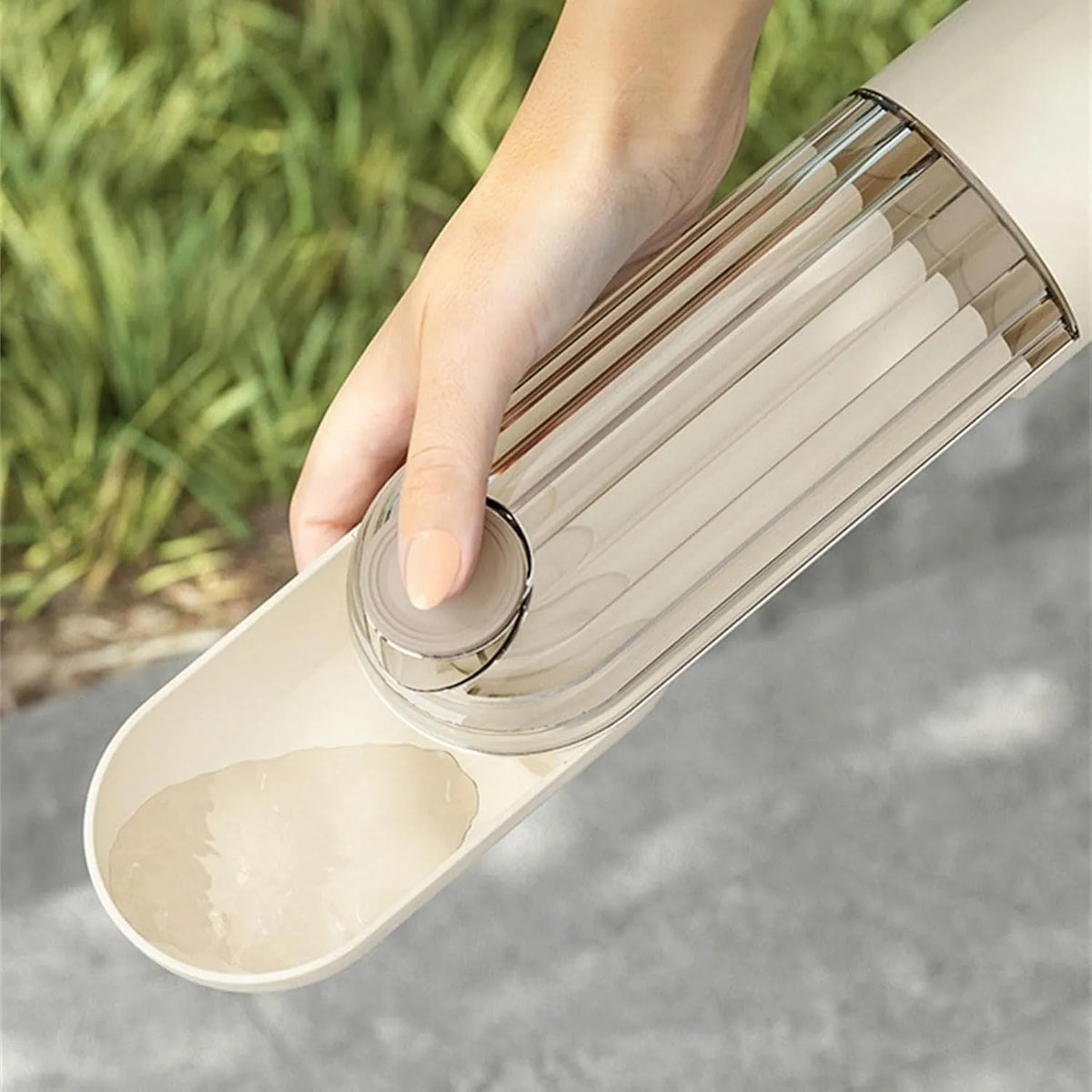 Beige foldable dog water bottle with food dispenser shown next to a dog on a walk