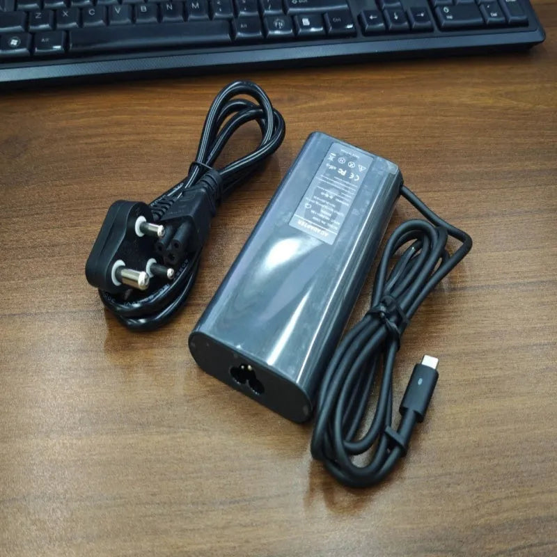 Black 65W USB-C laptop power adapter with UK plug and international travel adapters
