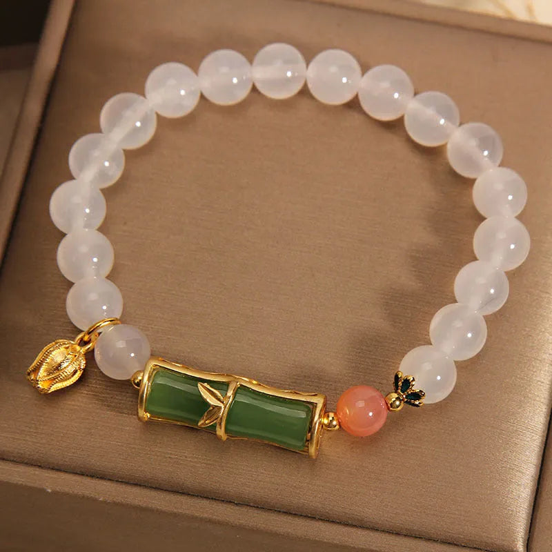 A women's bracelet with a textured jade bamboo bead and a white agate charm on a beaded string.