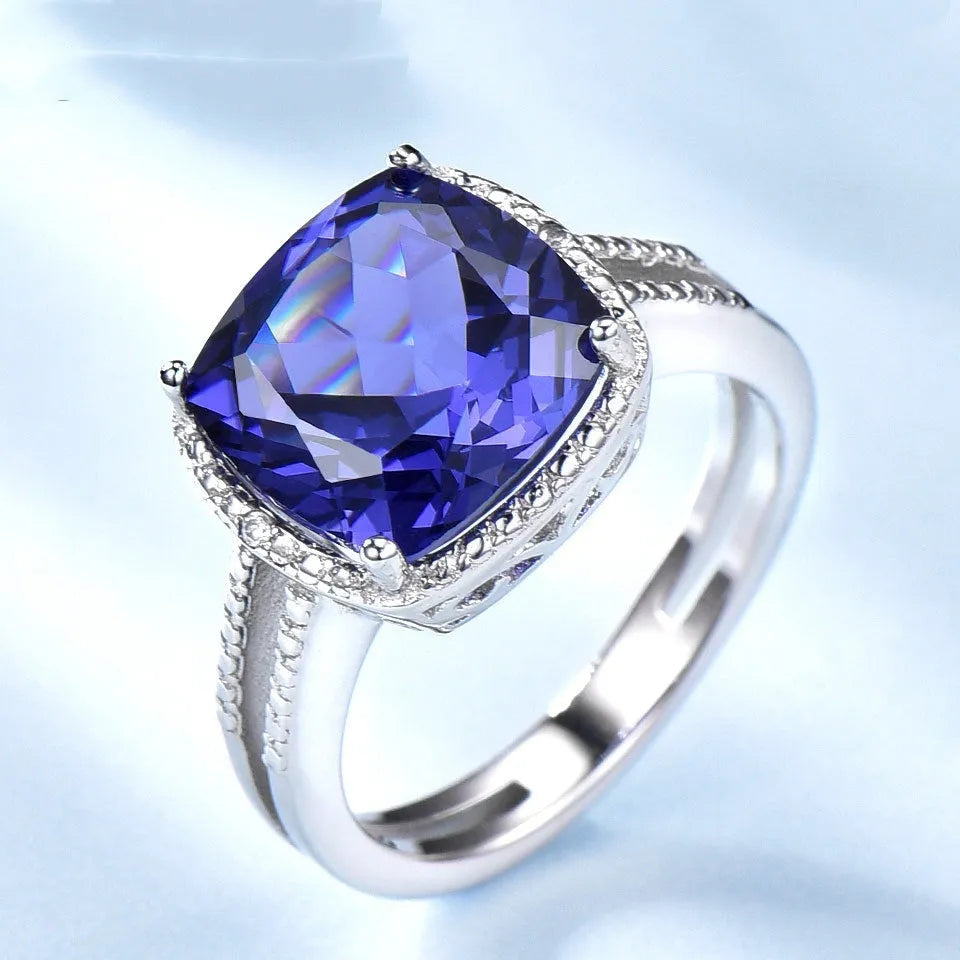Blue tanzanite gemstone set in a silver women's ring on a finger.