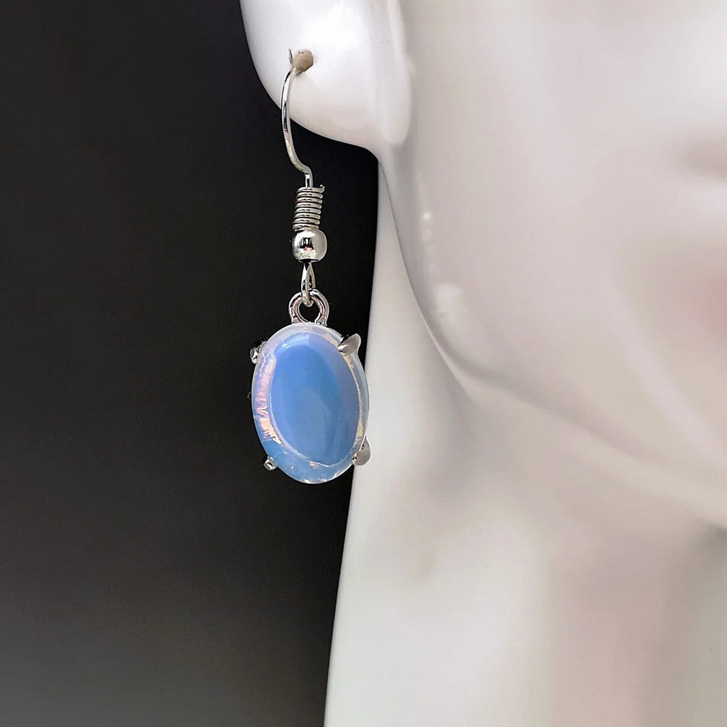 Pair of simple white drop-shaped retro earrings with a moonstone aesthetic on a plain background.
