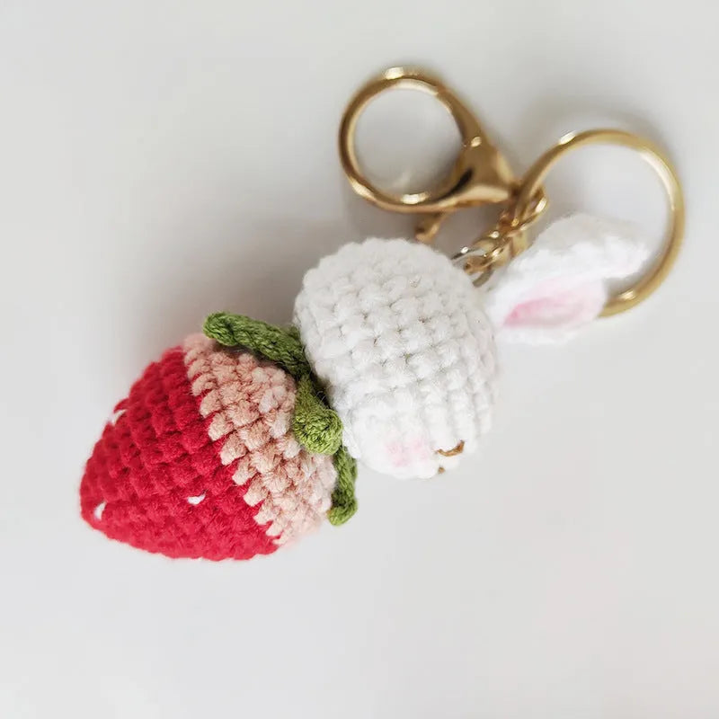 White hand-woven wire pendant charm with a cartoon rabbit and strawberry design on a key hook.