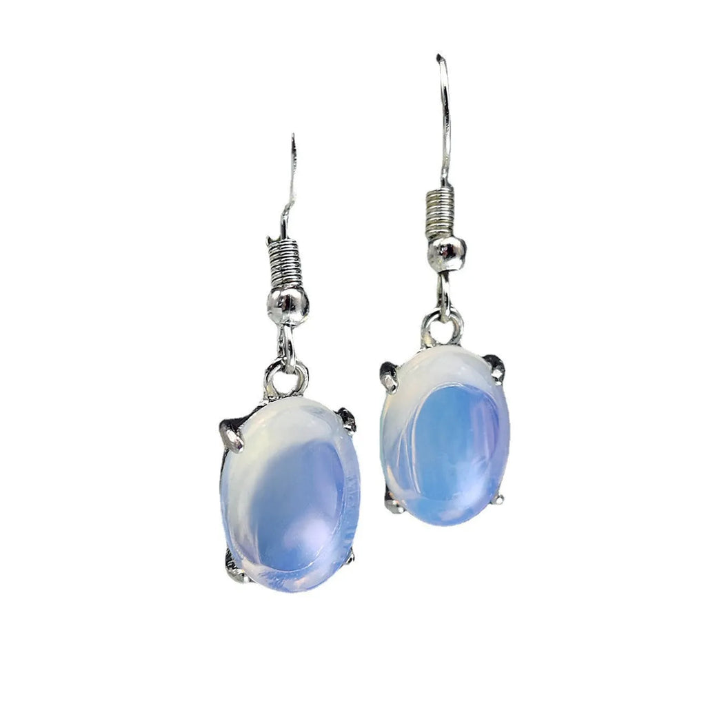 Pair of simple white drop-shaped retro earrings with a moonstone aesthetic on a plain background.