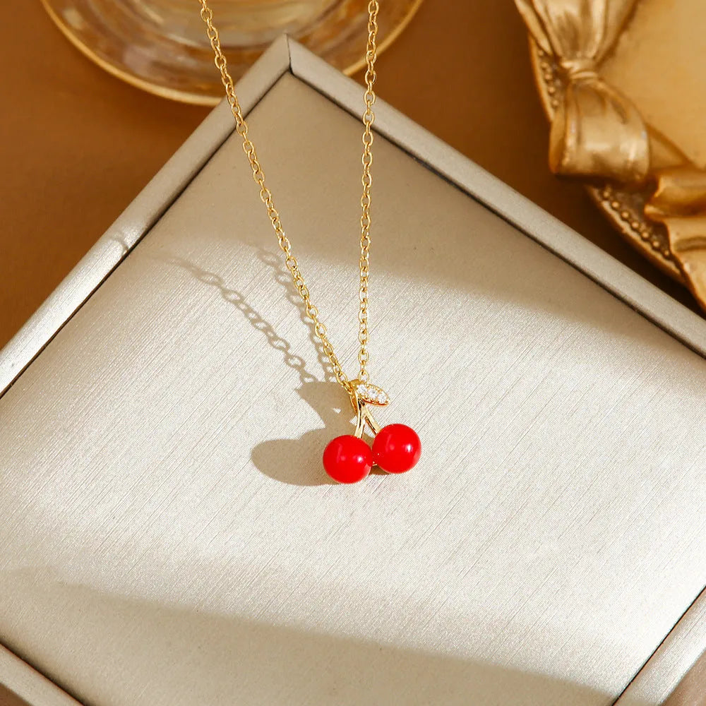 Titanium steel necklace with O-ring chain and a delicate cherry pendant in a gold-tone finish.
