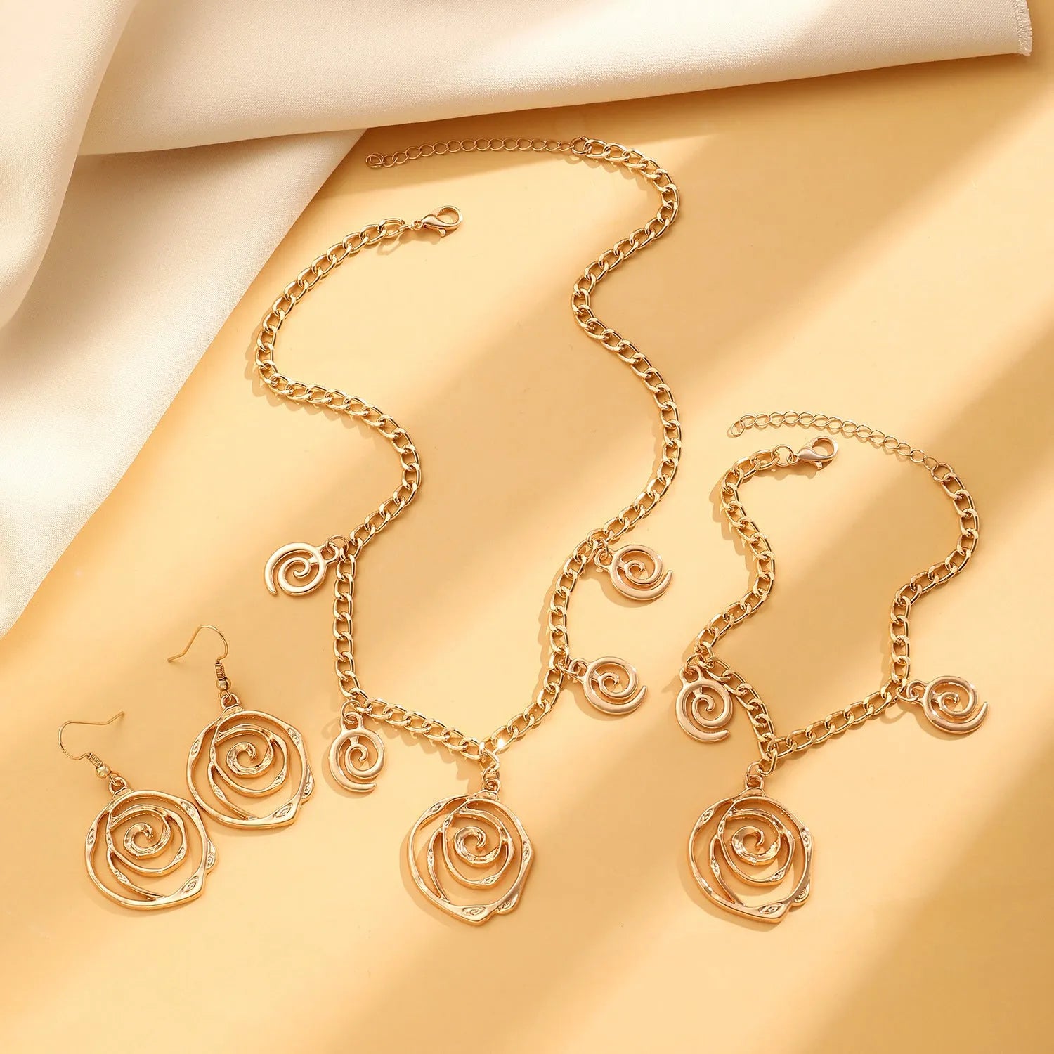 Women's spiral donut jewellery set showing necklace, bracelet and earrings in gold finish