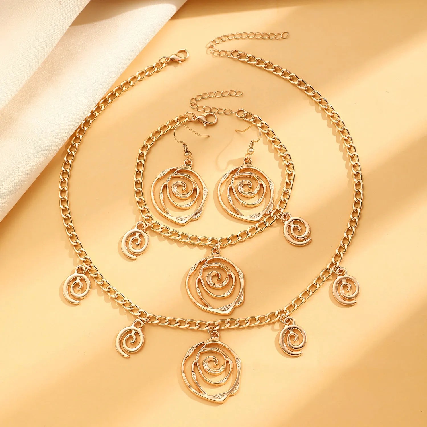 Women's spiral donut jewellery set showing necklace, bracelet and earrings in gold finish