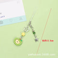 Red apple and strawberry plastic phone charm keychain with white rope on a mobile phone.