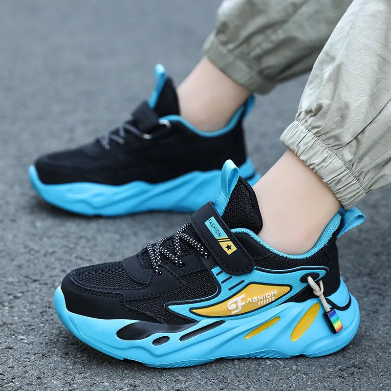 Boys sports running shoes in dark blue with a mesh upper and Velcro strap, shown on a hard ground surface.