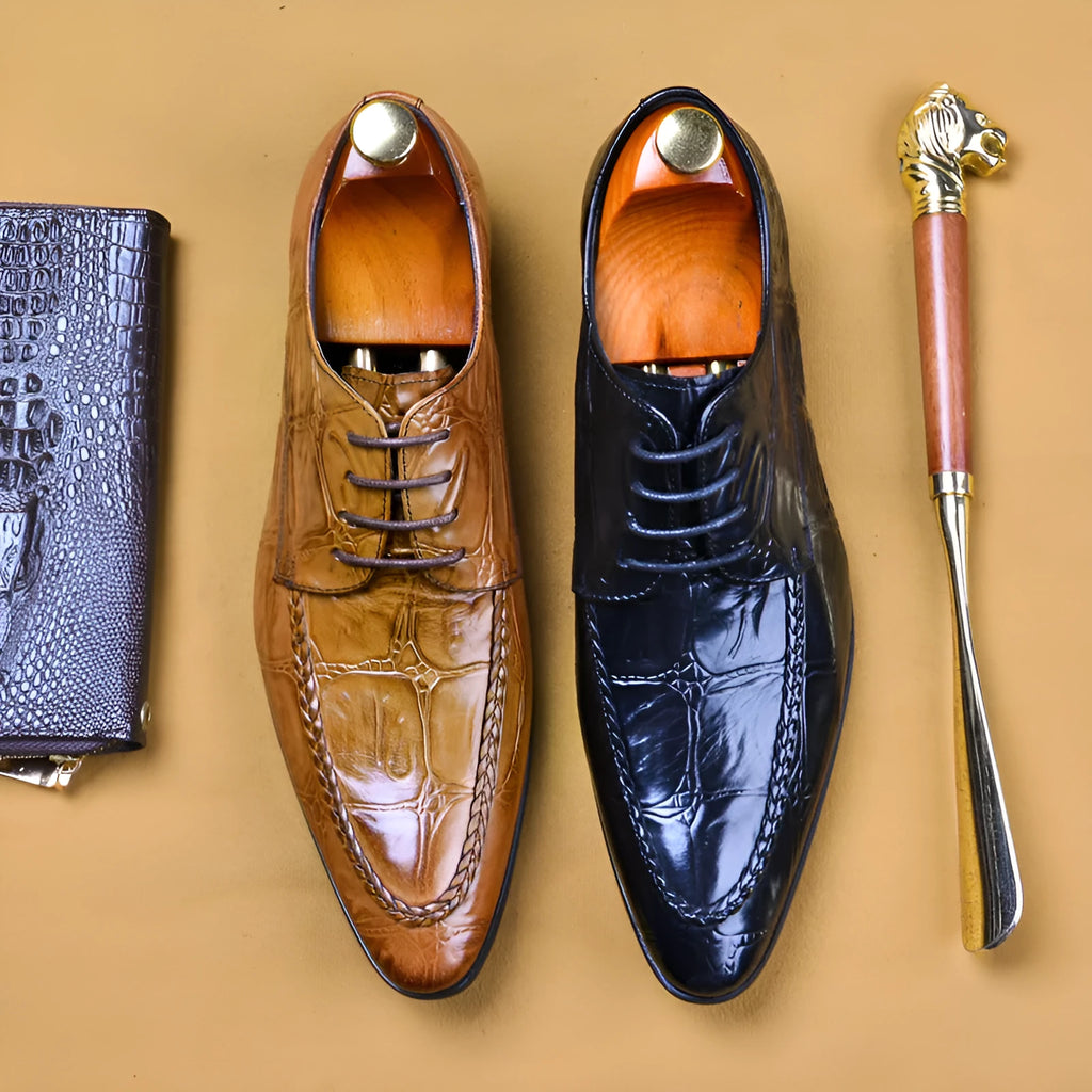 Men's black and brown leather loafers with alligator pattern and a horsebit buckle on a low rubber sole.