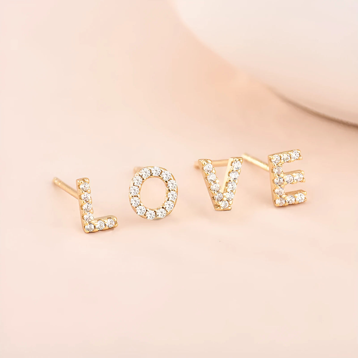 Gold plated alphabet letter earrings on a white background showing the full A-Z set with zircon detail.