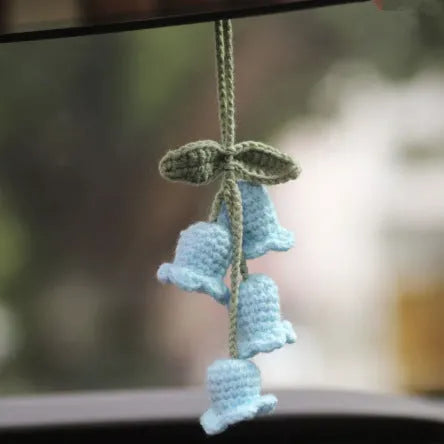 Green and white knitted wool car plant ornament with basin base and hanging rope.