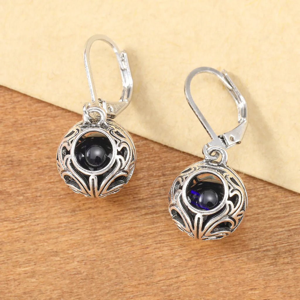 Silver geometric hollow pendant earrings with vintage engraving and a central blue gemstone on a zinc alloy setting.
