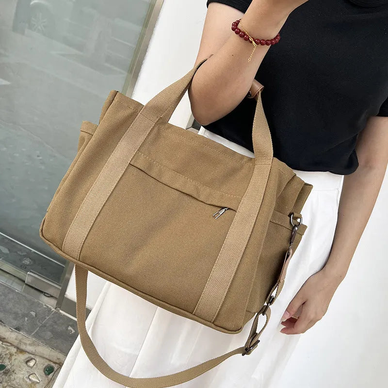 Canvas crossbody tote bag in khaki with open zipper showing internal organiser pockets.
