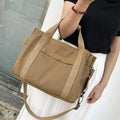 Canvas crossbody tote bag in khaki with open zipper showing internal organiser pockets.