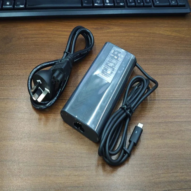 Black 65W USB-C laptop power adapter with UK plug and international travel adapters