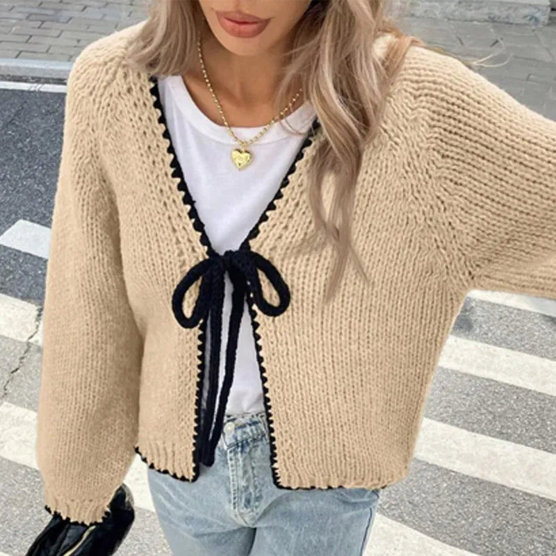 Gray lace-up cardigan sweater with crocheted flower detail and long sleeves on a hanger
