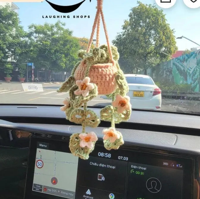 Green and white knitted wool car plant ornament with basin base and hanging rope.
