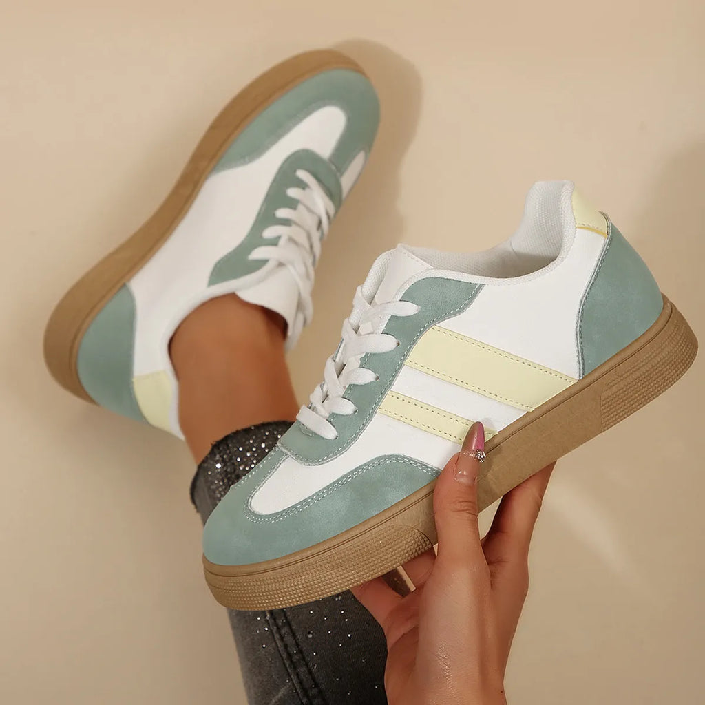 Green women's retro sneakers with cross-strap detail and leather stitching on a white background.