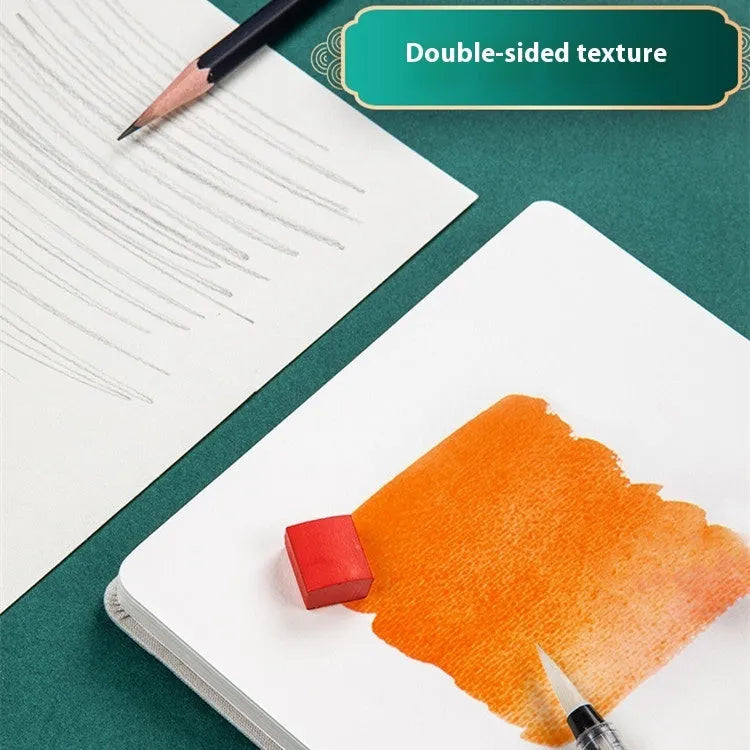 Feiluniao handmade fabric watercolour notebook open on a table with paintbrush.