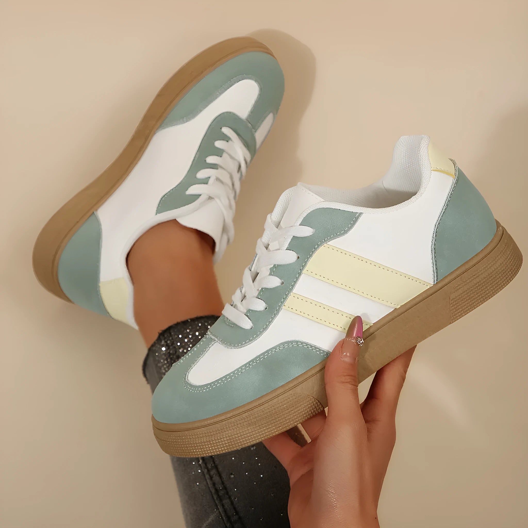 Green women's retro sneakers with cross-strap detail and leather stitching on a white background.