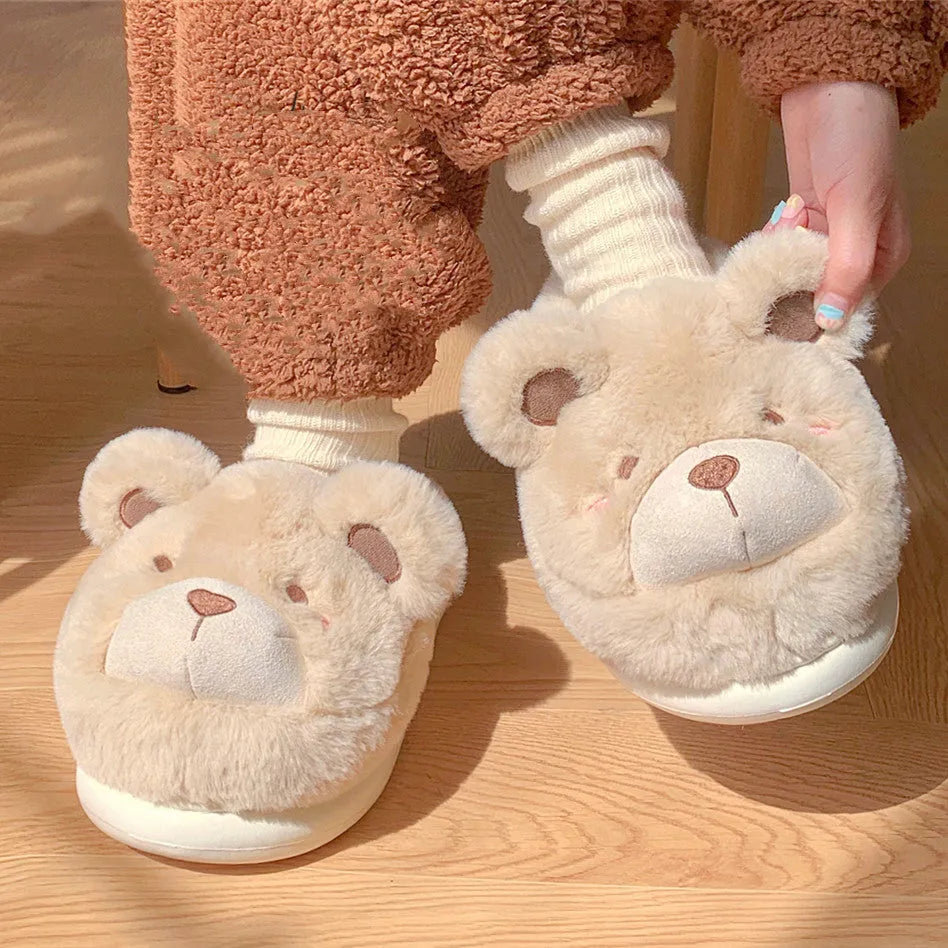 A pair of milky white baotou slippers with suede uppers and a cartoon pattern, showing the round toe shape.