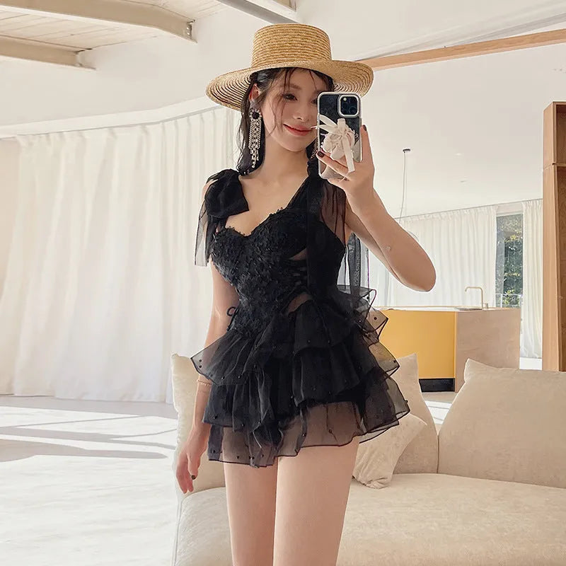 Black conservative one-piece swimsuit with gathered chest detail for tummy coverage.