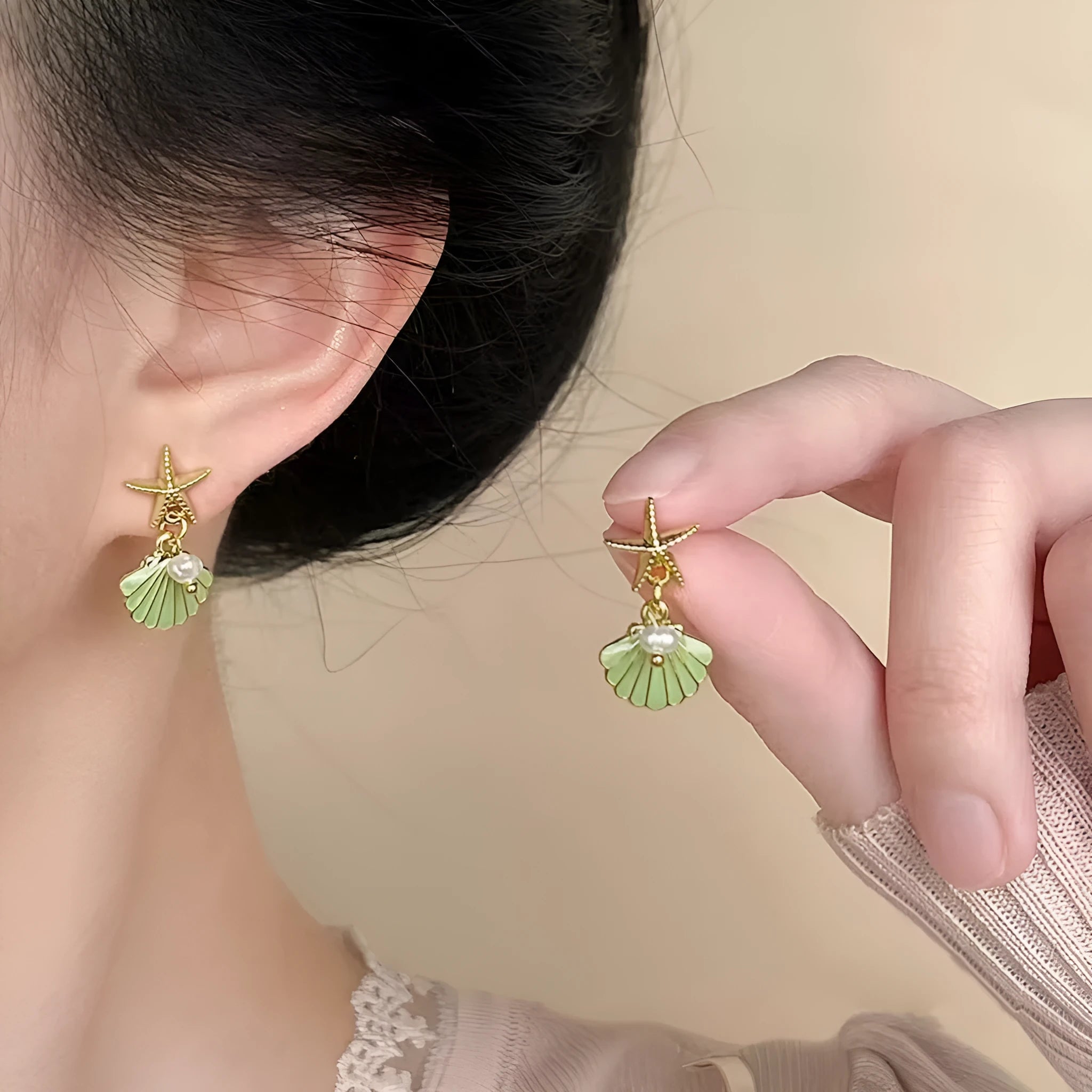 14K gold starfish shell earrings in light green on a white background