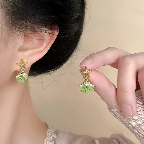 14K gold starfish shell earrings in light green on a white background