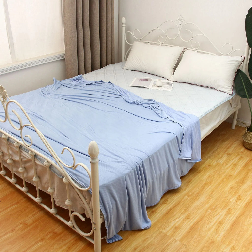 Blue cooling blanket with Japanese Q-Max fibres on a bed.