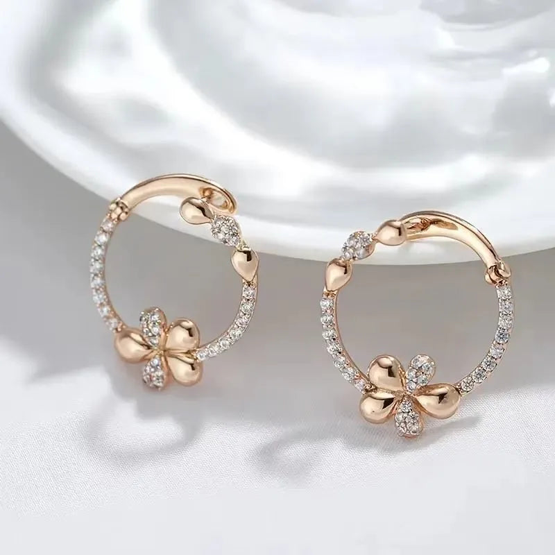 A pair of round gold-coloured hoop earrings with a geometric ring design on a plain background.