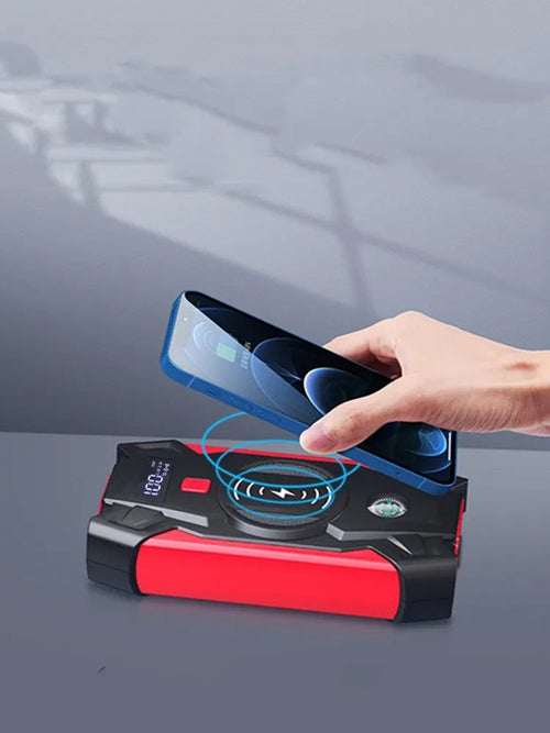 Red 12V portable car jump starter power bank with battery clips on a black background.