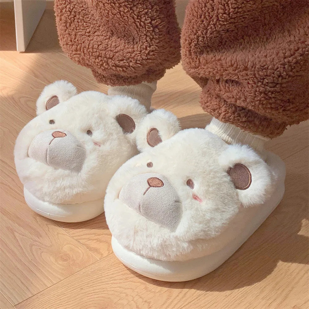 A pair of milky white baotou slippers with suede uppers and a cartoon pattern, showing the round toe shape.