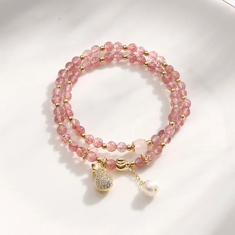 Women's geometric strawberry quartz crystal wallet bracelet on a wrist.