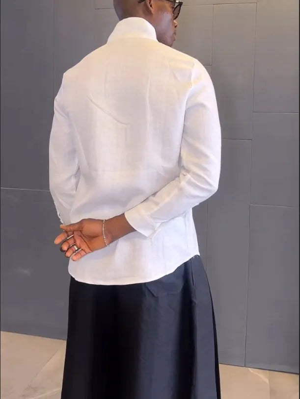 White asymmetric long sleeve shirt and black pleated trousers co-ord set on a hanger