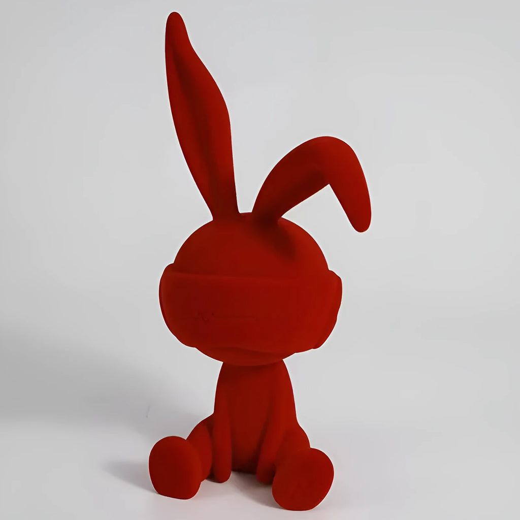 A resin table ornament of a rabbit wearing a suede blindfold, shown in blue, green, and red colour options.