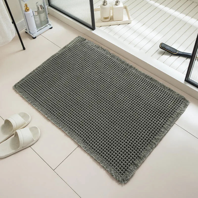Beige and white checkered woven polyester bathroom floor mat on tiles.