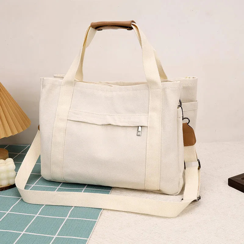 Canvas crossbody tote bag in khaki with open zipper showing internal organiser pockets.