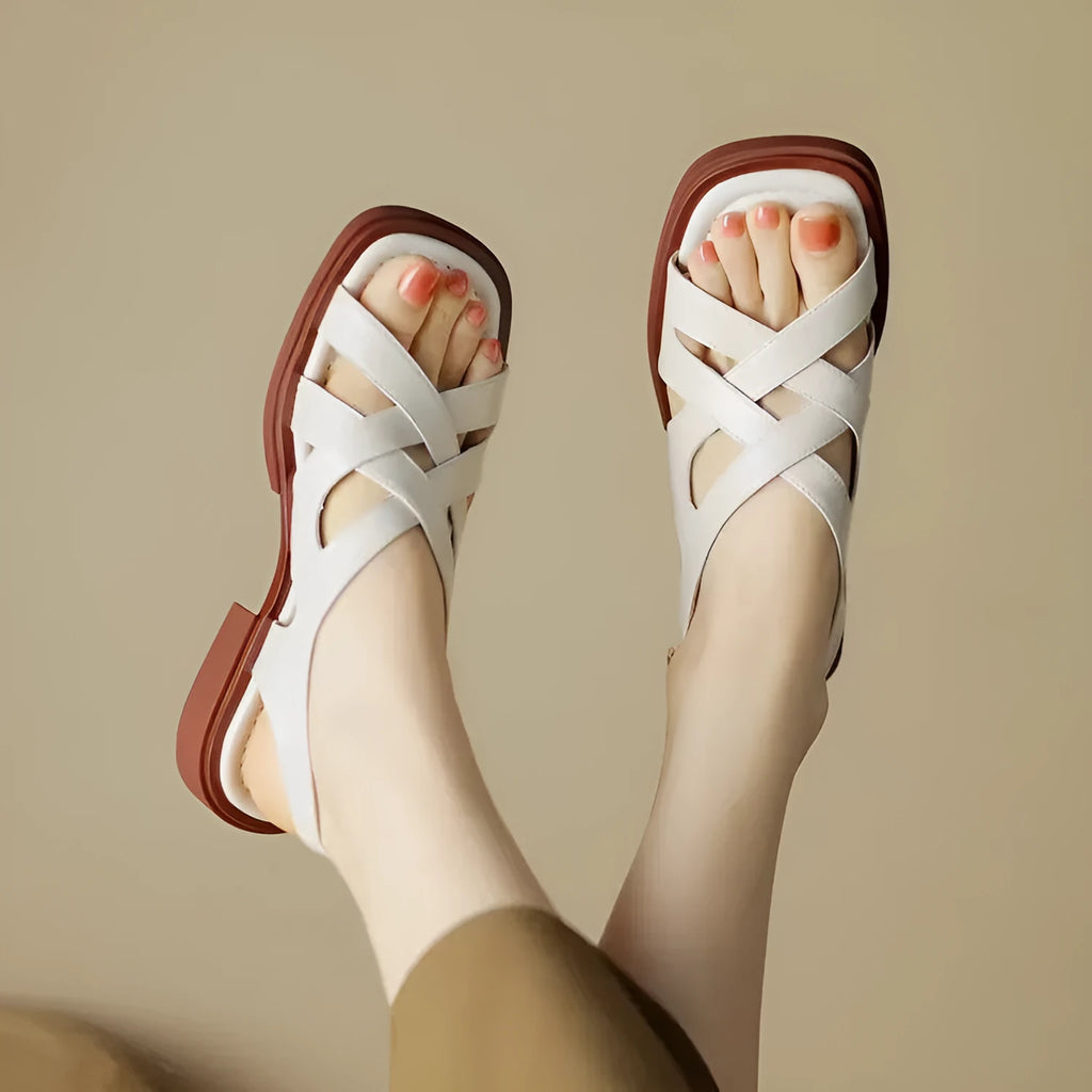Women's glossy patent leather square toe sandals with winding tape fastening on a neutral background.