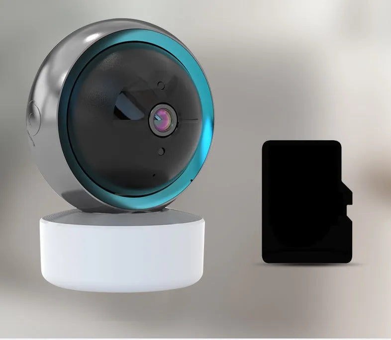 White 360-degree rotating indoor Wi-Fi security camera on a table with a UK plug power cord.