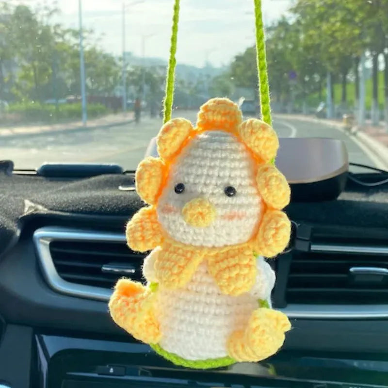 Green and white knitted wool car plant ornament with basin base and hanging rope.