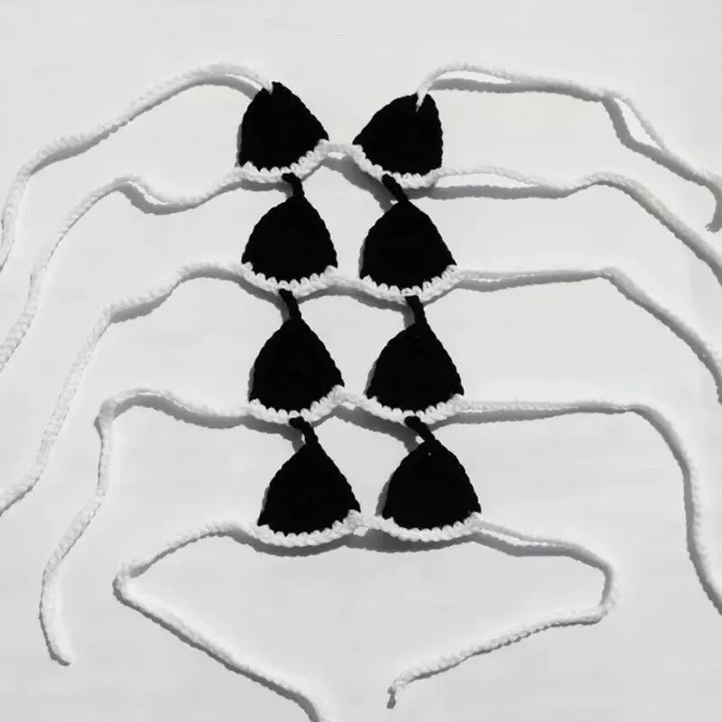 A cat wearing a black bikini bra costume for Halloween or party cosplay.