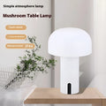 Decorative LED mushroom night light in green with warm white glow on a bedside table