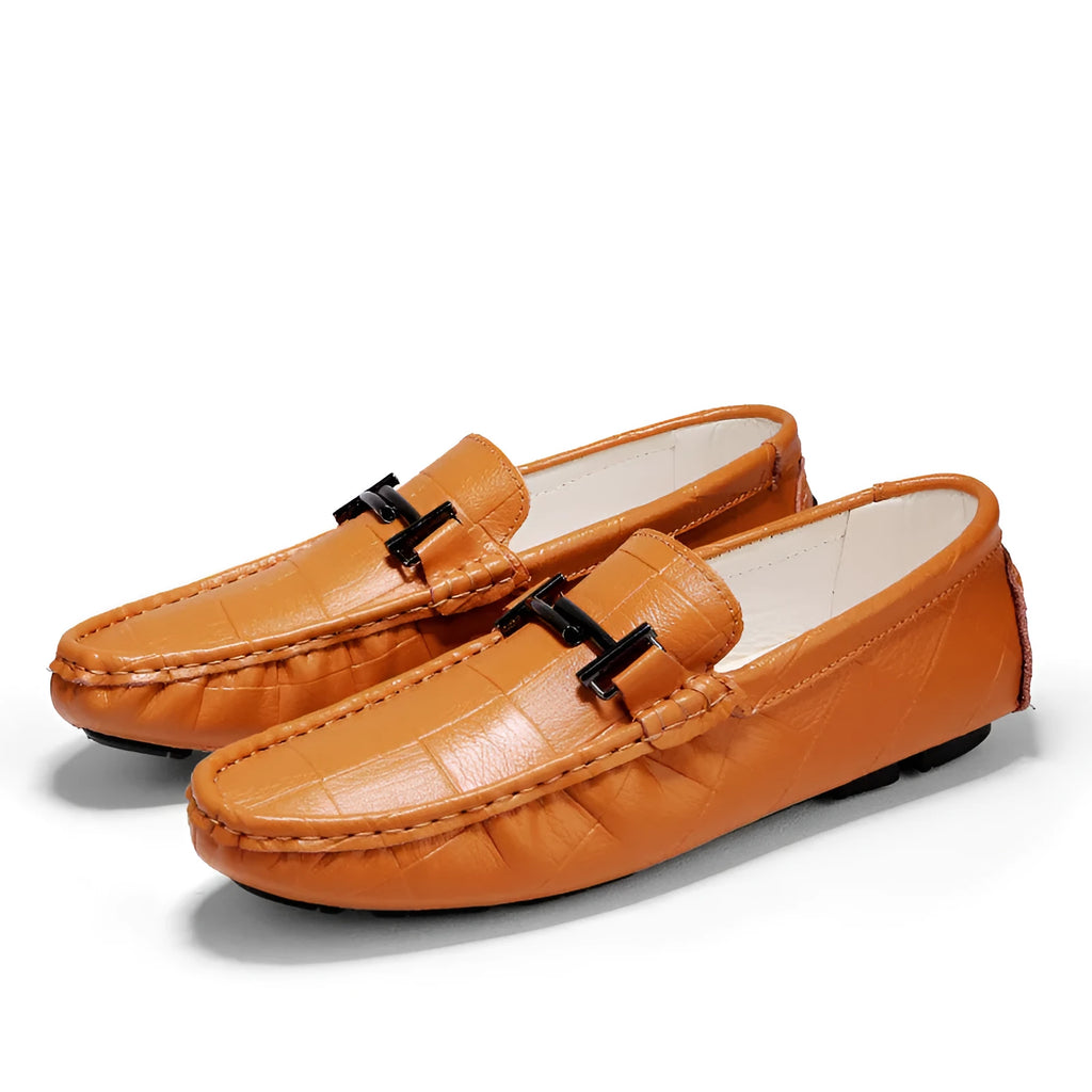 Men's brown leather casual shoes with a silver belt buckle on the side and a flat rubber sole.
