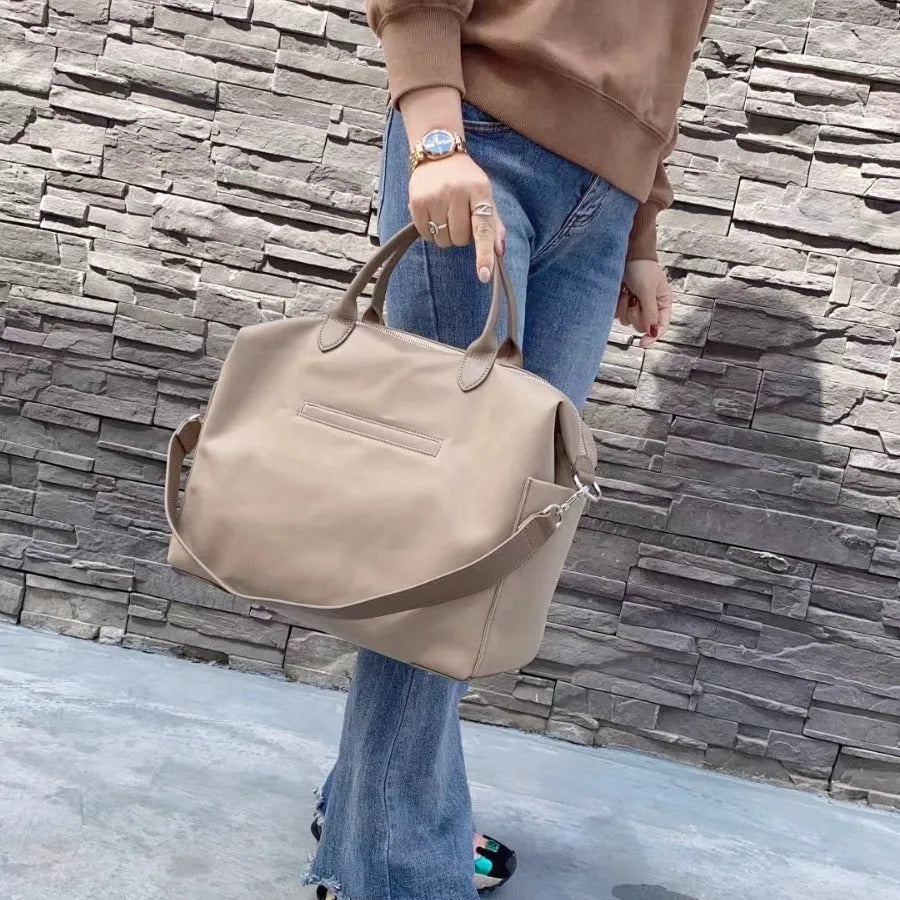 Black nylon waterproof shoulder bag with leather handles showing large open interior.