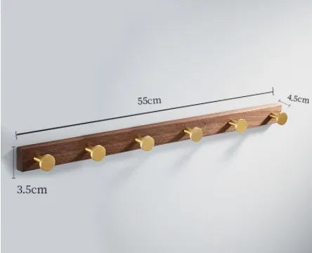 A row of black walnut bathroom clothes hooks with brushed brass metal details on a perforated mounting strip.
