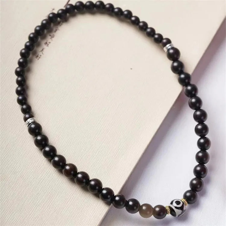 Close-up of a dark ebony wood bracelet with two smooth bead circles on a wrist.