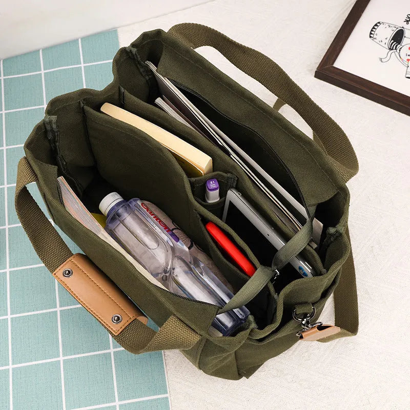 Canvas crossbody tote bag in khaki with open zipper showing internal organiser pockets.