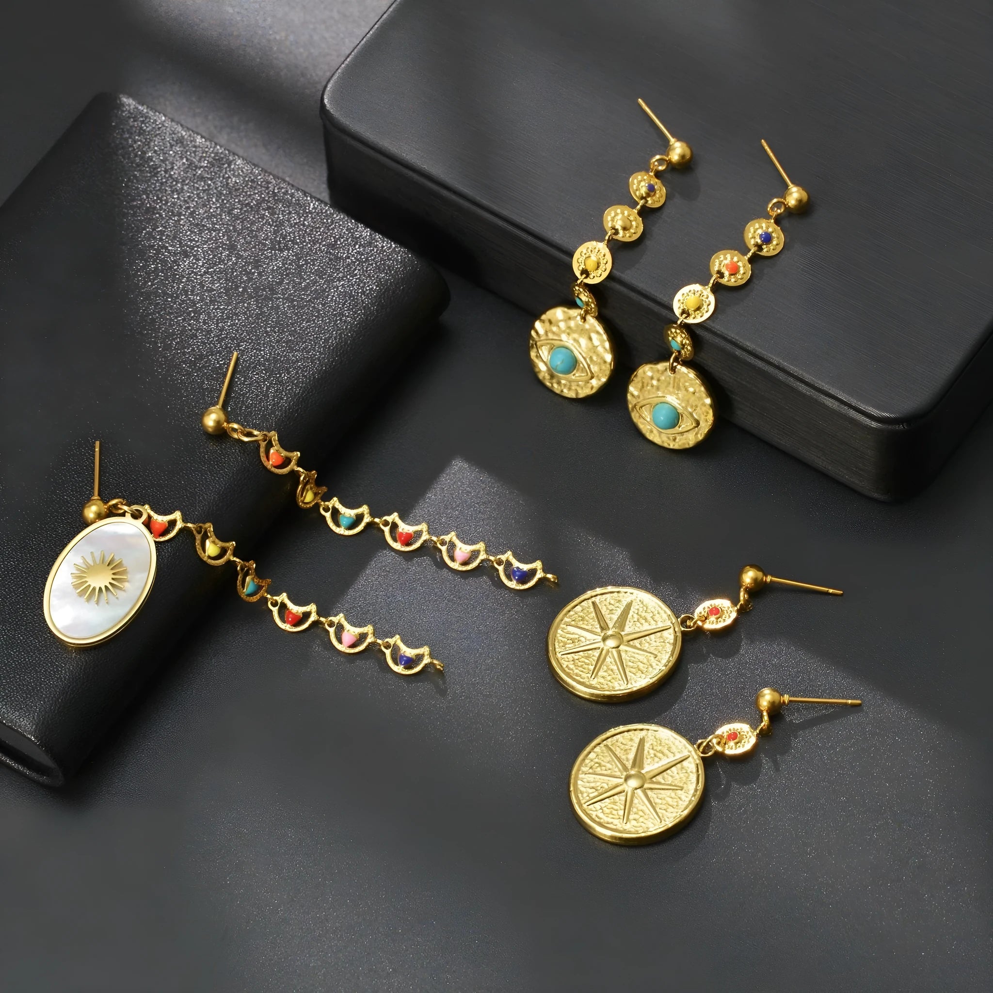 Three pairs of geometric stainless steel earrings showing Eight Awn Star, Eye, and Shell Sun designs